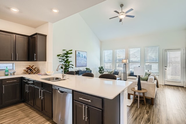 kitchen with dishwasher, sink, kitchen peninsula, light hardwood / wood-style floors, and lofted ceiling