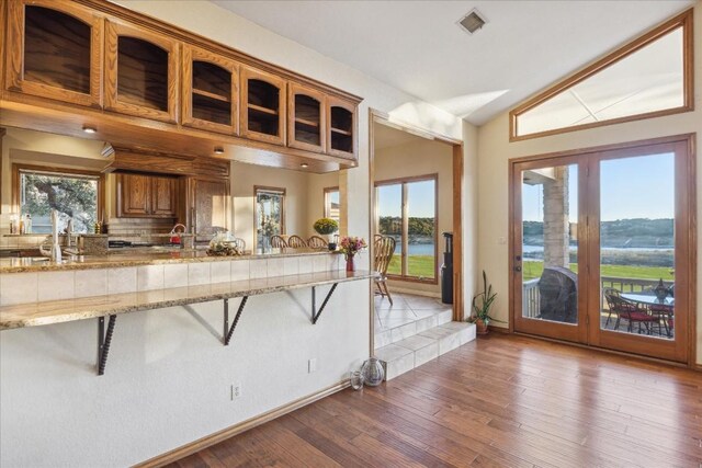 20625 Highland Lake Loop, Lago Vista, TX 78645 - kitchen featuring french doors, vaulted ceiling, a breakfast bar area, glass insert cabinets, and wood finished floors
