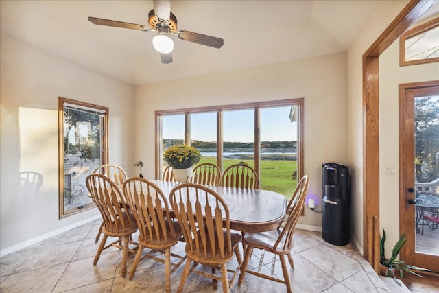 tiled dining room with a water view and ceiling fan