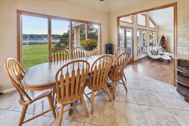 dining area with light hardwood / wood-style flooring, a water view, and lofted ceiling