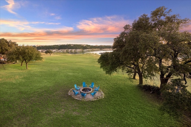 yard at dusk featuring a water view and an outdoor fire pit