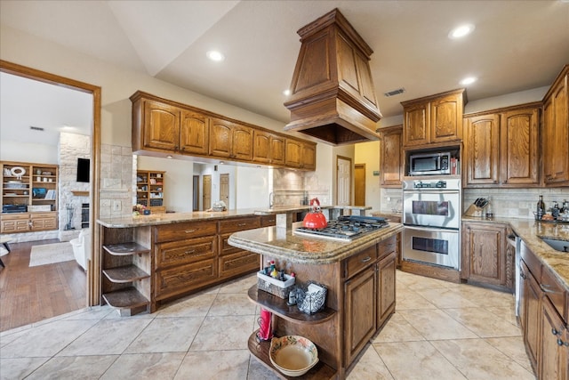 kitchen featuring stainless steel appliances, backsplash, kitchen peninsula, lofted ceiling, and a kitchen island