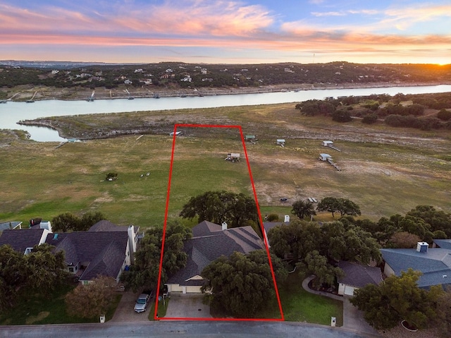 aerial view at dusk featuring a water view