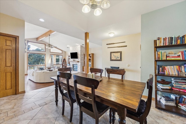 dining room with a large fireplace, lofted ceiling with beams, ceiling fan with notable chandelier, and light hardwood / wood-style floors