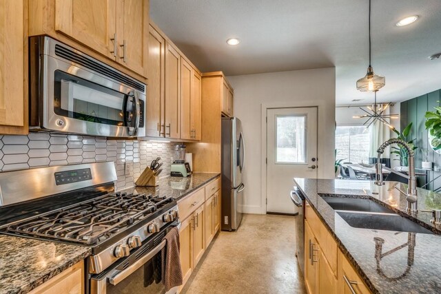 kitchen with pendant lighting, dark stone countertops, sink, and appliances with stainless steel finishes