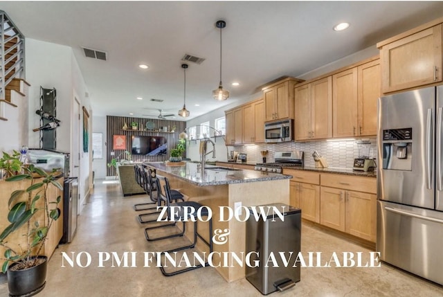 kitchen featuring visible vents, dark stone countertops, decorative light fixtures, a kitchen island with sink, and stainless steel appliances