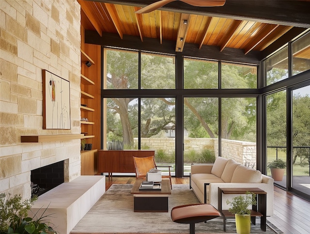 sunroom / solarium with a stone fireplace, a wealth of natural light, and wood ceiling