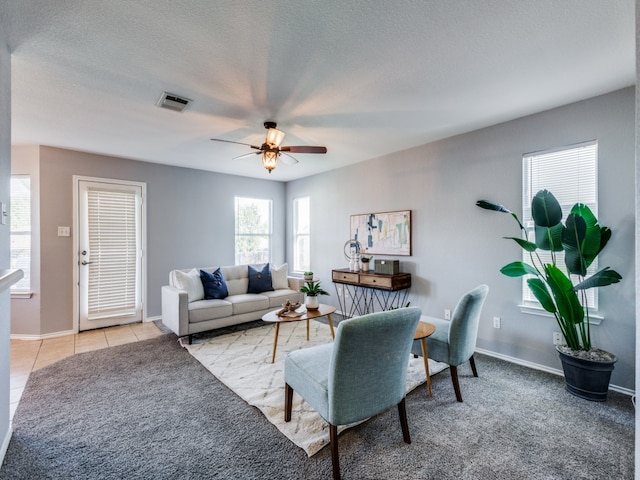 living area featuring carpet floors, baseboards, a ceiling fan, and visible vents