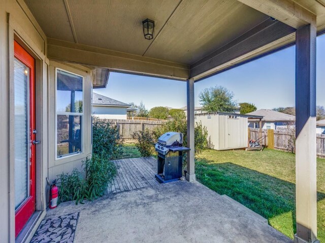 view of patio with an outdoor structure, a shed, a fenced backyard, and a grill