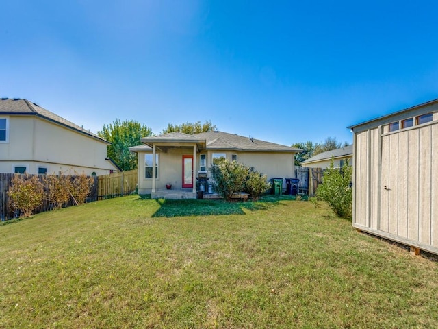 rear view of property featuring a lawn and a fenced backyard