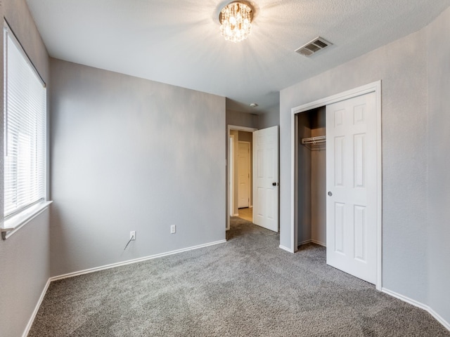 unfurnished bedroom with a chandelier, carpet, visible vents, and baseboards