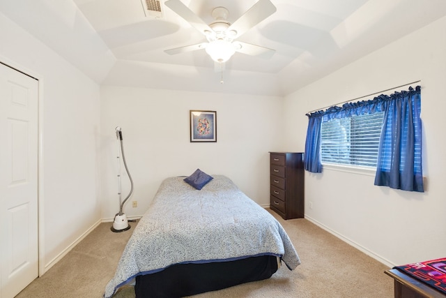 bedroom with light carpet, a raised ceiling, and ceiling fan