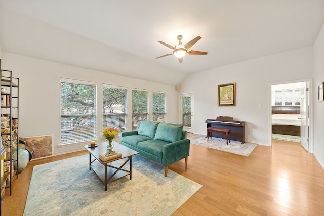 living room featuring ceiling fan, light hardwood / wood-style floors, and vaulted ceiling