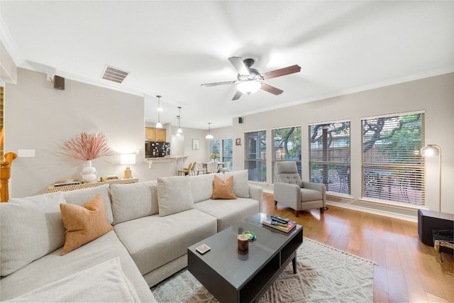 living room featuring hardwood / wood-style floors, ceiling fan, and crown molding