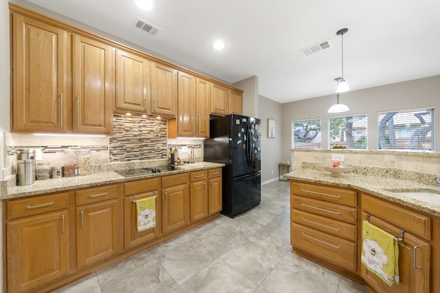 kitchen with backsplash, light stone counters, hanging light fixtures, and black appliances