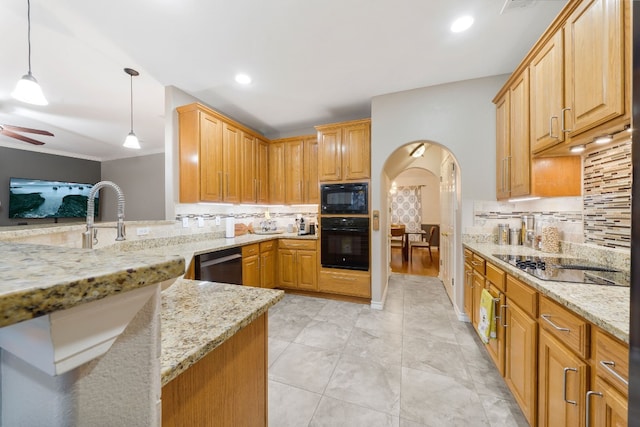 kitchen featuring backsplash, light stone counters, hanging light fixtures, and black appliances