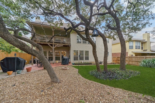 rear view of house featuring a patio, a balcony, and a lawn