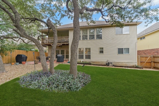 rear view of property featuring a lawn, a patio area, and a balcony