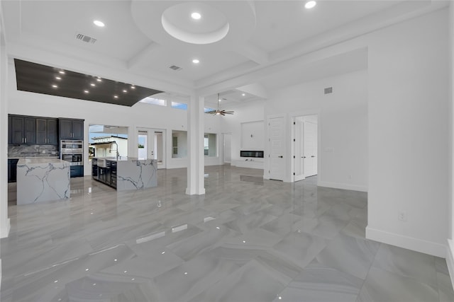 unfurnished living room featuring ceiling fan, sink, and a high ceiling