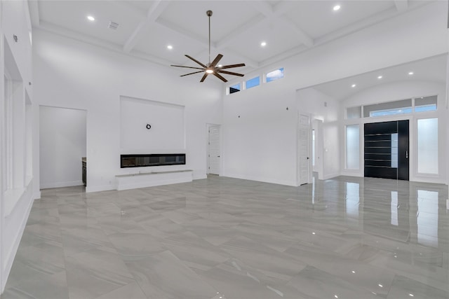 unfurnished living room with ceiling fan, coffered ceiling, beamed ceiling, and a high ceiling