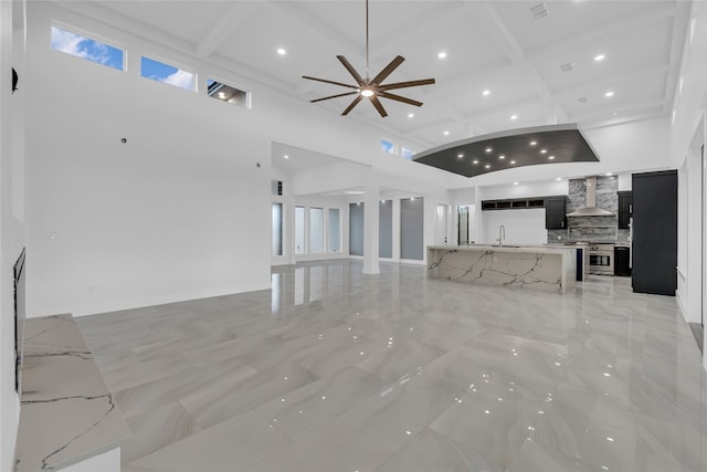 unfurnished living room with a wealth of natural light, coffered ceiling, beamed ceiling, and a high ceiling