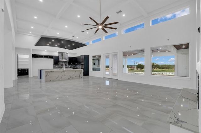 unfurnished living room with beamed ceiling, a towering ceiling, and coffered ceiling