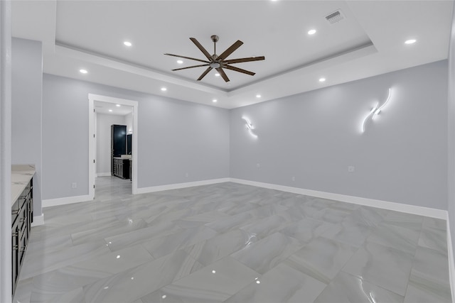 unfurnished living room with a raised ceiling and ceiling fan