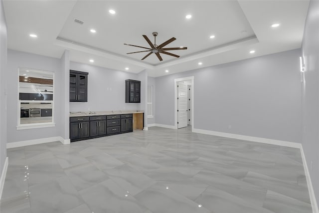 unfurnished living room with a tray ceiling and ceiling fan