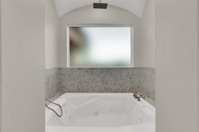 bathroom with a washtub and lofted ceiling