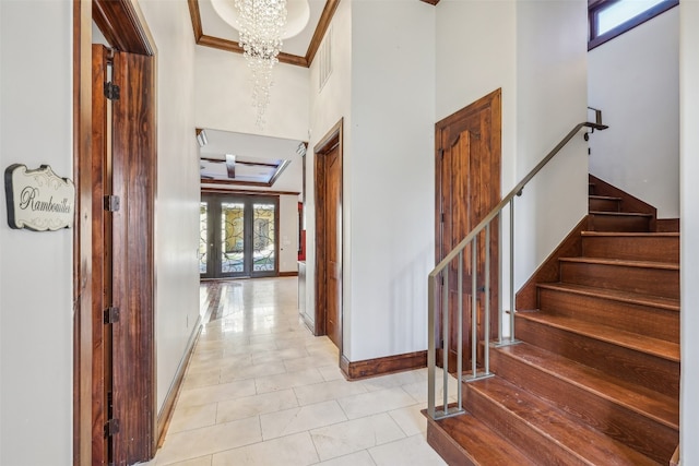 interior space with french doors, crown molding, a notable chandelier, a high ceiling, and light tile patterned flooring