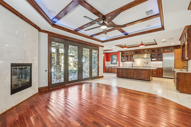 unfurnished living room with sink, french doors, beamed ceiling, and light hardwood / wood-style flooring