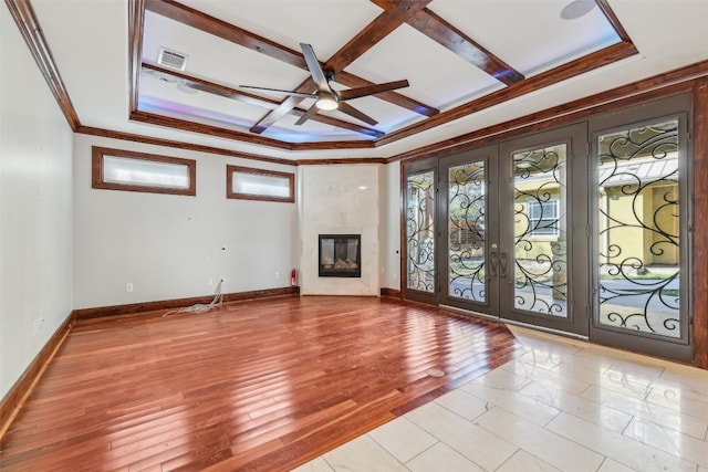 unfurnished living room featuring french doors, light wood-type flooring, coffered ceiling, beam ceiling, and a premium fireplace