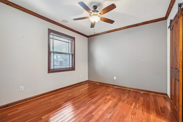 unfurnished room featuring a barn door, ceiling fan, crown molding, and wood-type flooring