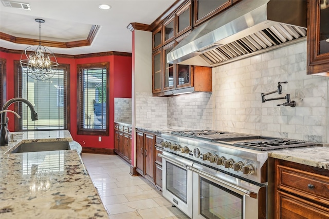 kitchen with sink, wall chimney range hood, backsplash, double oven range, and decorative light fixtures