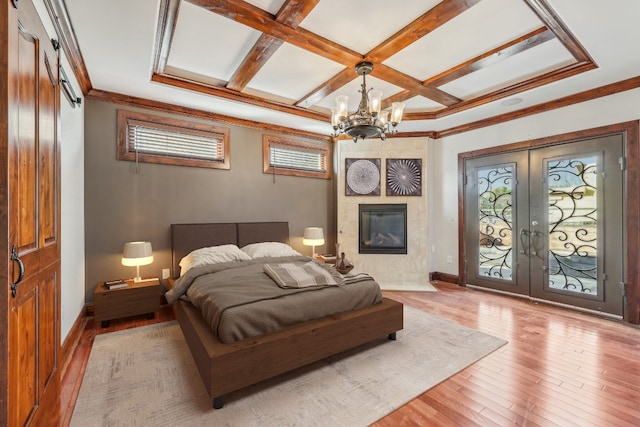 bedroom featuring access to exterior, french doors, coffered ceiling, light hardwood / wood-style floors, and a fireplace