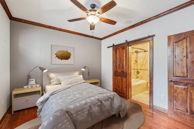 bedroom featuring ensuite bath, ceiling fan, a barn door, hardwood / wood-style flooring, and ornamental molding