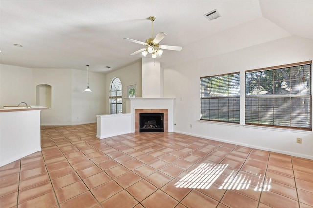 unfurnished living room with a tile fireplace, ceiling fan, sink, lofted ceiling, and light tile patterned flooring