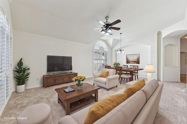 carpeted living room with ceiling fan with notable chandelier and lofted ceiling