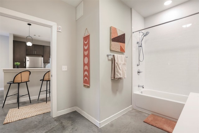 bathroom with concrete flooring and tiled shower / bath