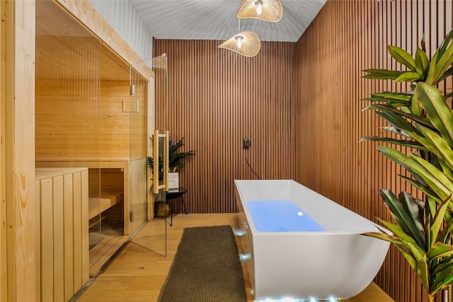 bathroom featuring a tub to relax in, wood-type flooring, and wood walls