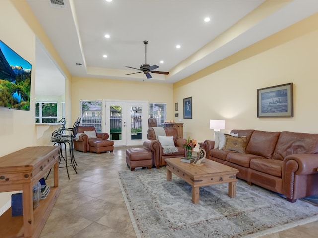 living room featuring a tray ceiling, ceiling fan, plenty of natural light, and french doors