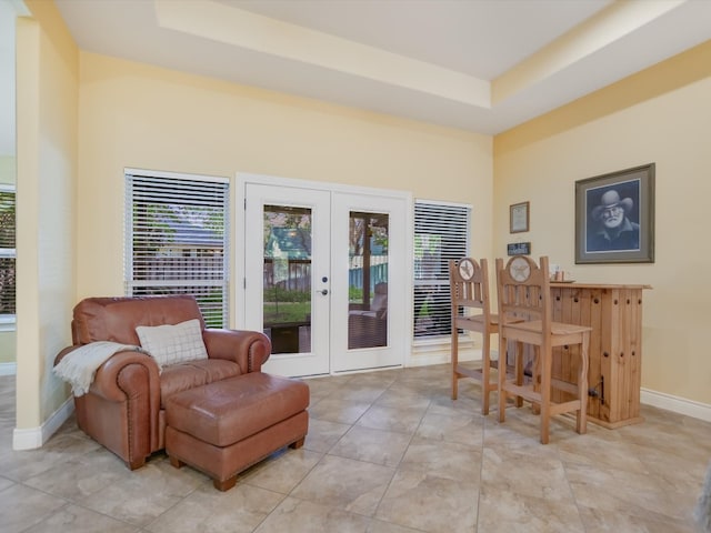 living area featuring a raised ceiling, french doors, and light tile patterned floors