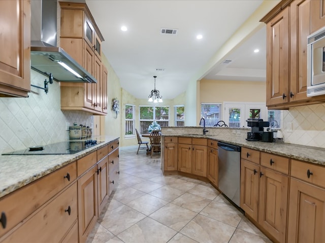 kitchen with wall chimney range hood, sink, decorative backsplash, light stone countertops, and appliances with stainless steel finishes