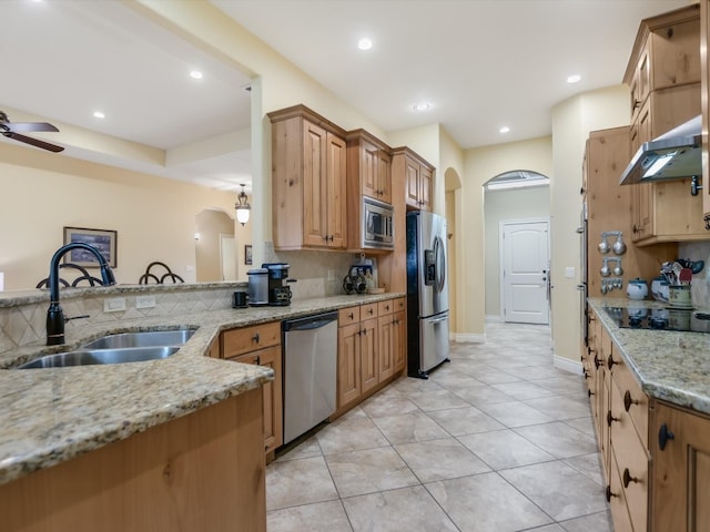 kitchen featuring exhaust hood, sink, tasteful backsplash, light stone counters, and stainless steel appliances