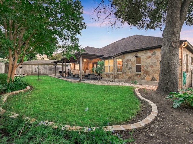 back house at dusk with a lawn and a patio area