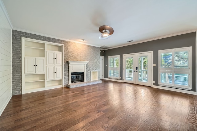 unfurnished living room with crown molding, dark hardwood / wood-style flooring, a fireplace, and french doors