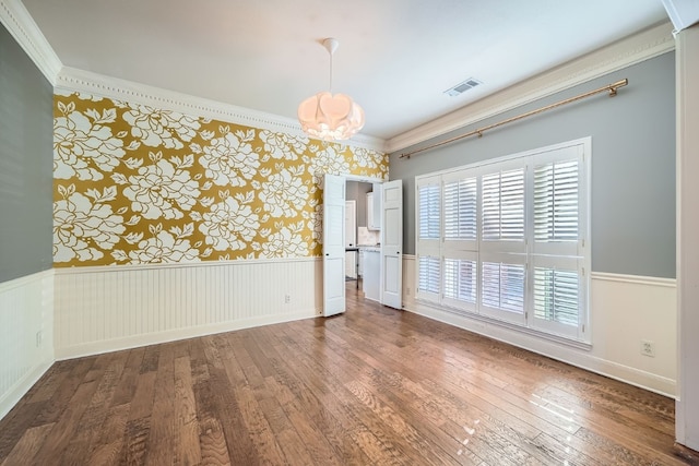 empty room featuring hardwood / wood-style floors, an inviting chandelier, and ornamental molding