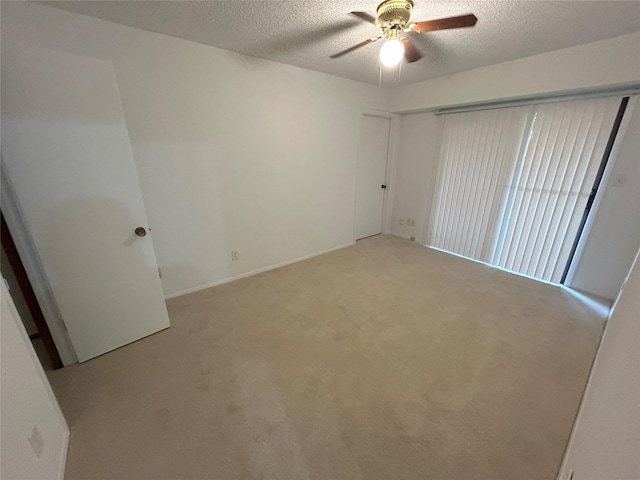 empty room featuring a textured ceiling, light colored carpet, and ceiling fan