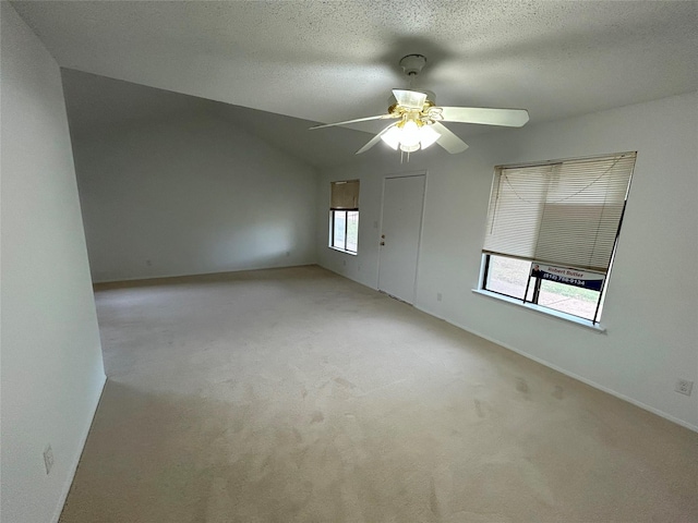 spare room with a textured ceiling, ceiling fan, light carpet, and vaulted ceiling