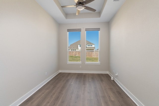 spare room with a tray ceiling, ceiling fan, and hardwood / wood-style flooring